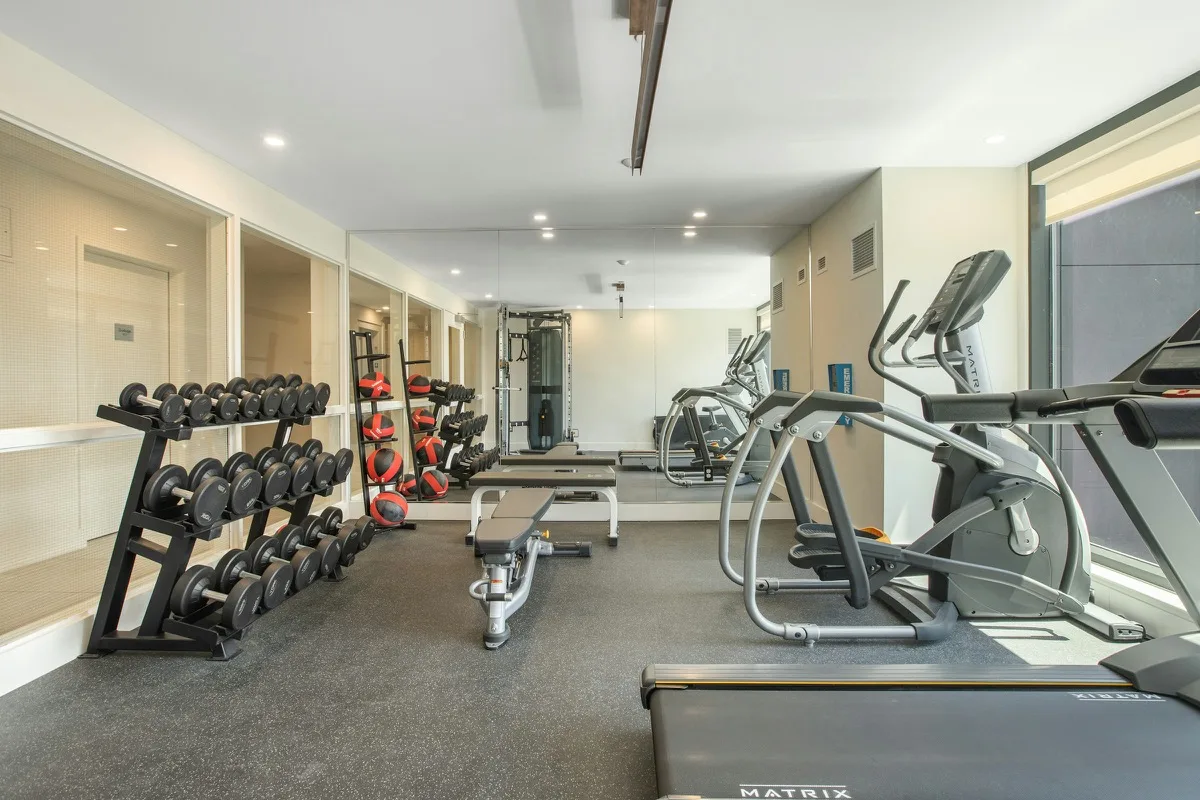Piccolo corner fitness in hotel con tapis roulant, cyclette e pesi liberi in uno spazio comune luminoso
