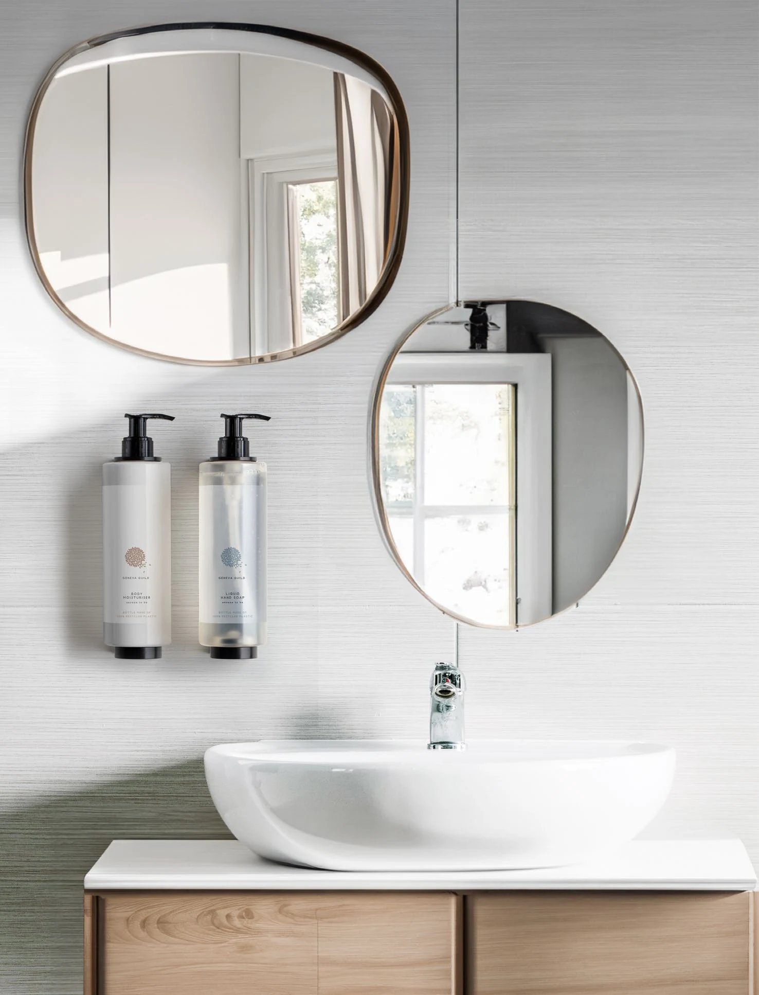 Due dispenser Geneva Guild installati accanto a specchi rotondi