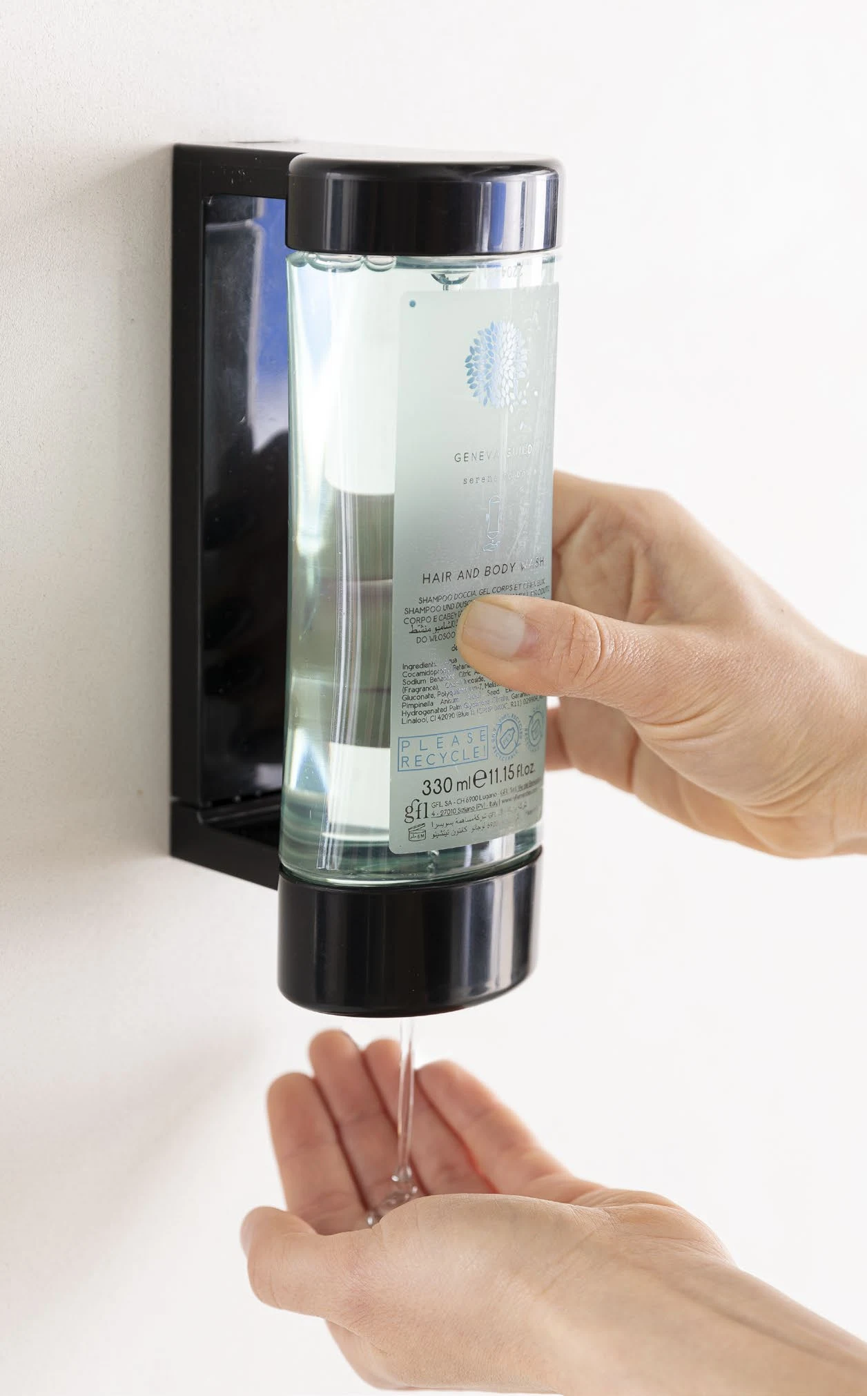 Mano che comprime un dispenser Geneva Guild a parete