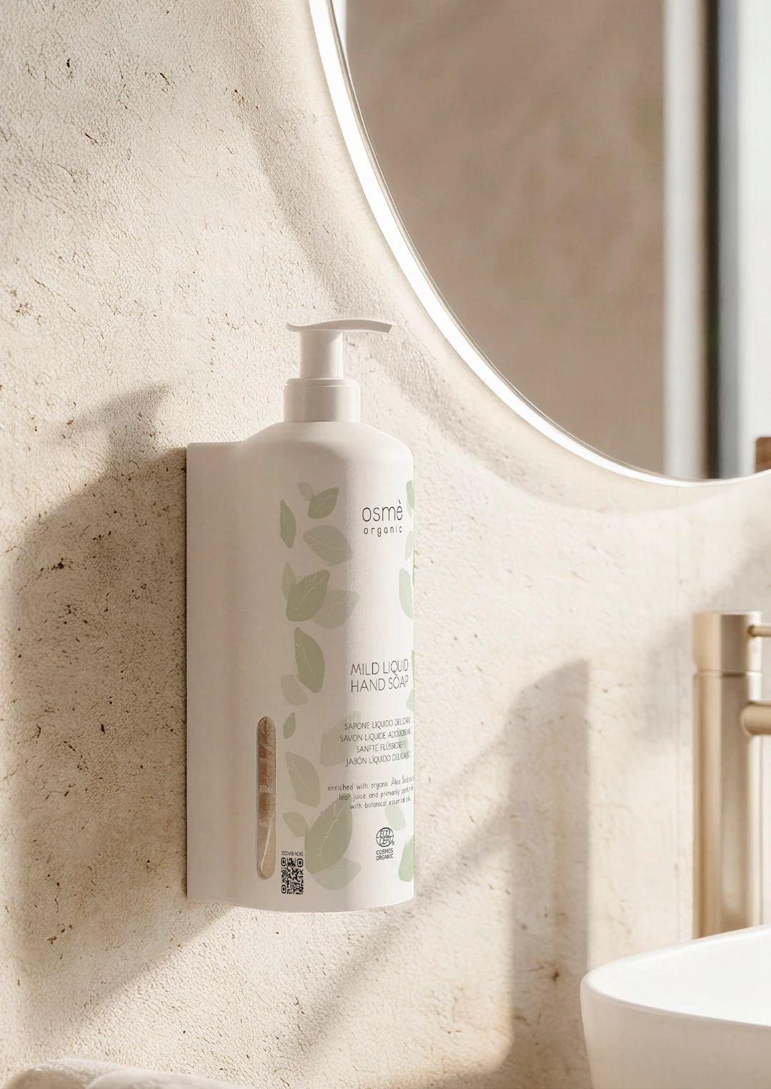 Dispenser Osmè installato accanto allo specchio di un bagno chiaro