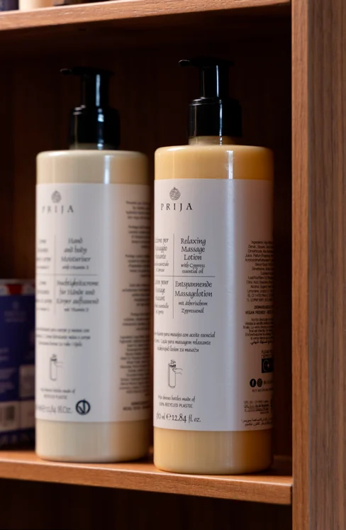 Flaconi Prija integri fotografati su uno scaffale in legno
